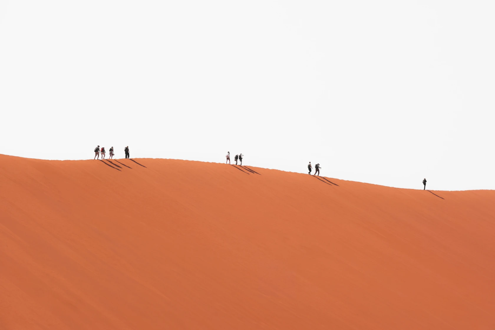 Eine Gruppe von Menschen wandert auf einer Sanddüne