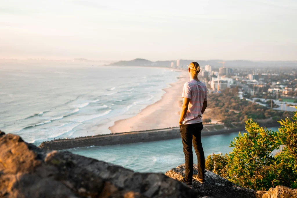 Ein Mann steht auf einer Klippe und bestaunt die im Hintergrund gelegene Strandszenerie in Australien